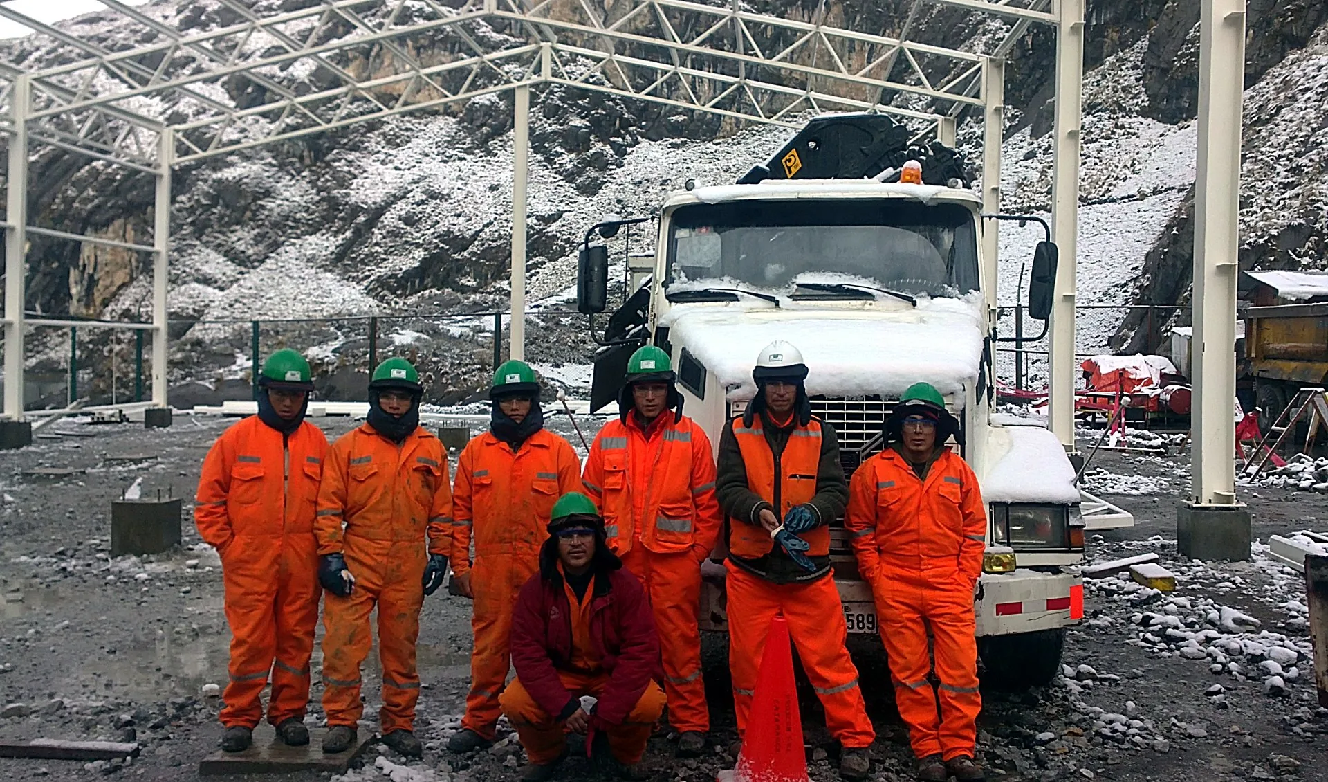 Cuadrilla de PROYCON con equipo de protección personal completo junto a mixer en unidad minera